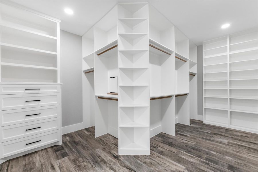 Spacious walk-in closet featuring custom shelving, ample hanging space, and elegant wood flooring for a luxurious storage solution.