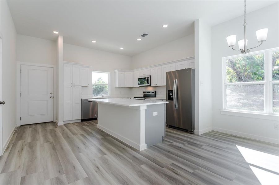 Kitchen featuring white cabinetry, stainless steel appliances, a healthy amount of sunlight, and a kitchen island