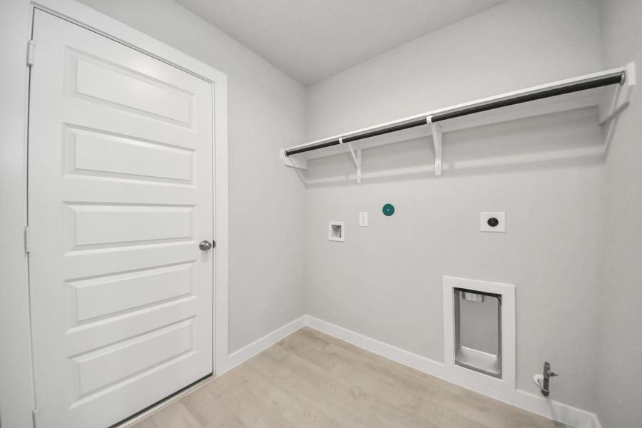 A perfect blend of functionality and comfort. Capture the essence of easy living with a first-floor laundry room, thoughtfully equipped with shelving for effortless organization. Both electric and gas connections available. Sample photo of completed home with similar floor plan. Actual colors and selections may vary.