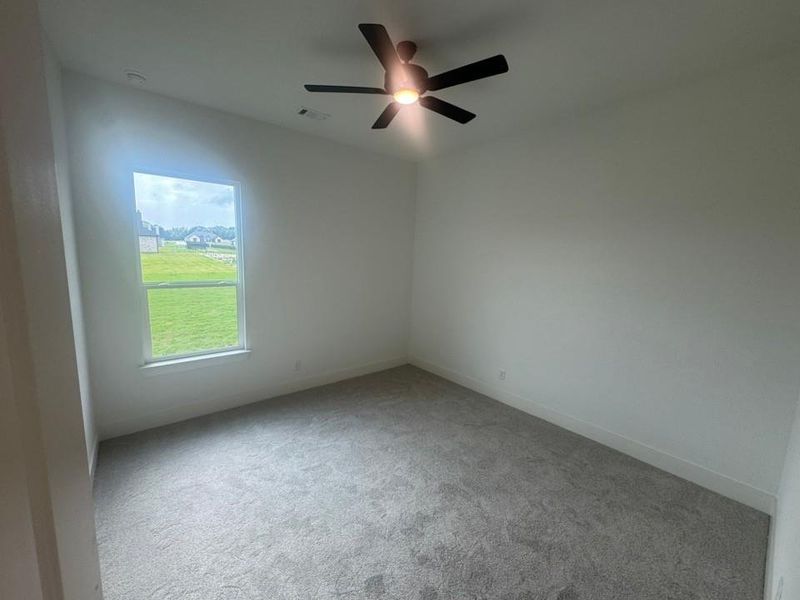 Carpeted room featuring a single window, white walls, and a ceiling fan with integrated lighting