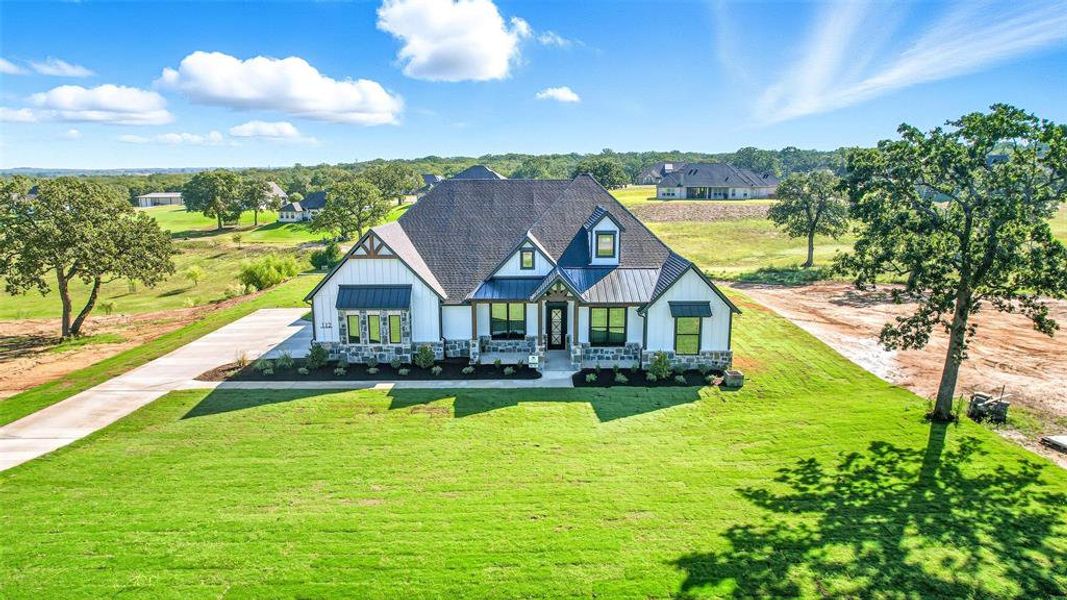 View of front of house featuring a standing seam roof, covered porch, a front lawn, and a metal roof View of front of house featuring a standing seam roof, covered porch, a front lawn, and a metal roof