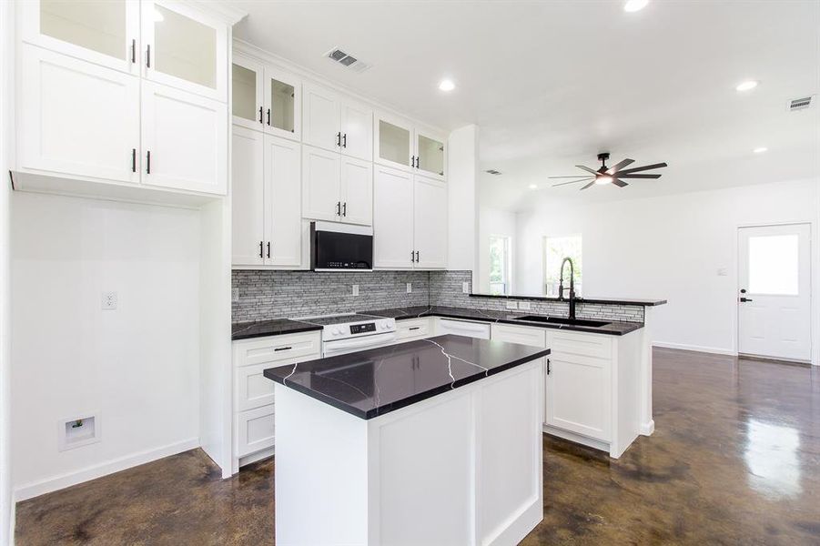 Kitchen featuring ceiling fan, white electric range, sink, kitchen peninsula, and backsplash