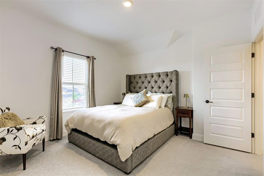 A plush bed anchors this bedroom, complemented by a serene window and soft, neutral carpeting. A plush bed anchors this bedroom, complemented by a serene window and soft, neutral carpeting.