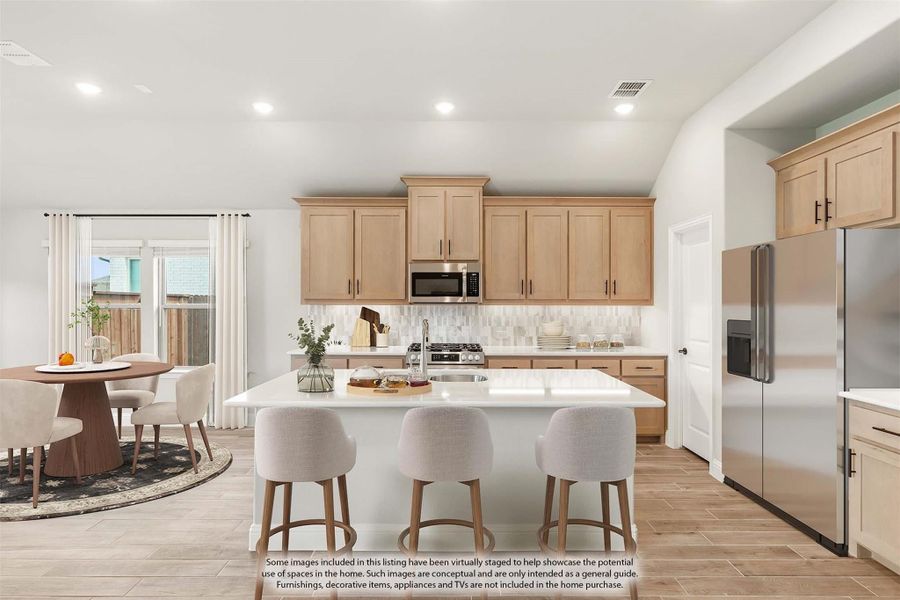 Kitchen with light wood cabinets, center island with seating, stainless steel appliances, and adjacent dining area