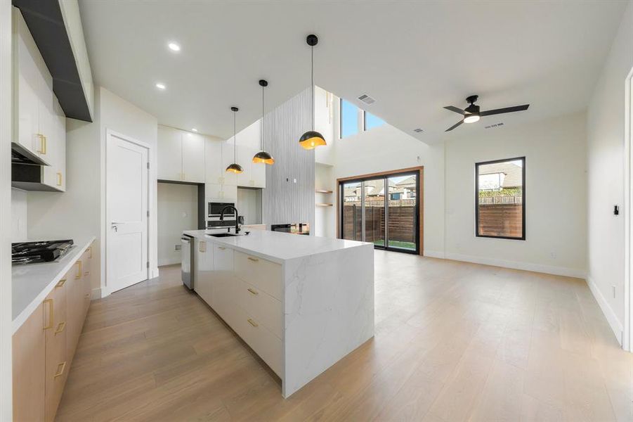 Kitchen with pendant lighting, a center island with sink, light stone counters, light wood finished floors, and recessed lighting Kitchen with pendant lighting, a center island with sink, light stone counters, light wood finished floors, and recessed lighting