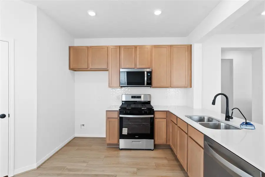 Efficiently designed kitchen maximizes every inch of space, with Woodmont Dakota cabinetry in Barley stain, Whirlpool stainless steel appliances, and Silestone countertops. The perfect functional hub for daily cooking. Efficiently designed kitchen maximizes every inch of space, with Woodmont Dakota cabinetry in Barley stain, Whirlpool stainless steel appliances, and Silestone countertops. The perfect functional hub for daily cooking.