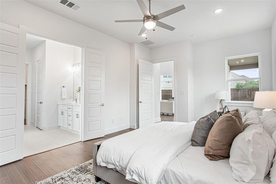 Bedroom with ensuite bath, ceiling fan, and light wood-type flooring