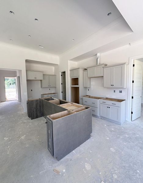 Spacious kitchen featuring light-toned cabinetry, recessed lighting, crown molding, and a central island structure