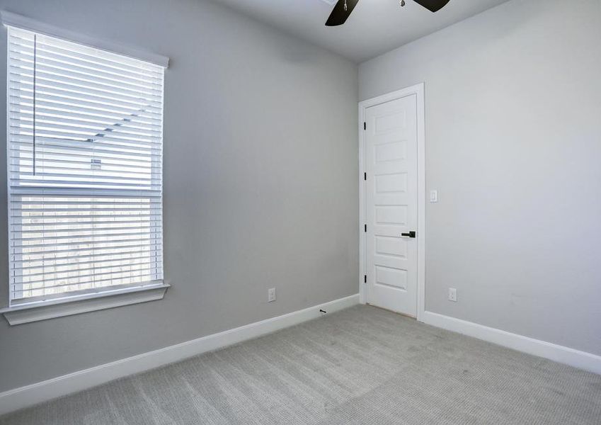 Secondary bedroom with plush carpet and a ceiling fan.