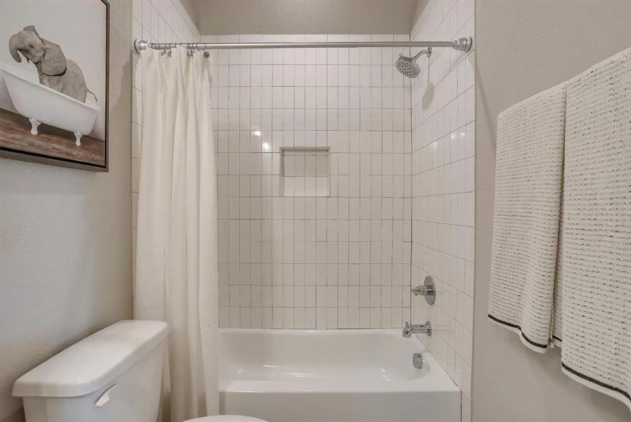 Bathroom with shower / bath combination with curtain and toilet