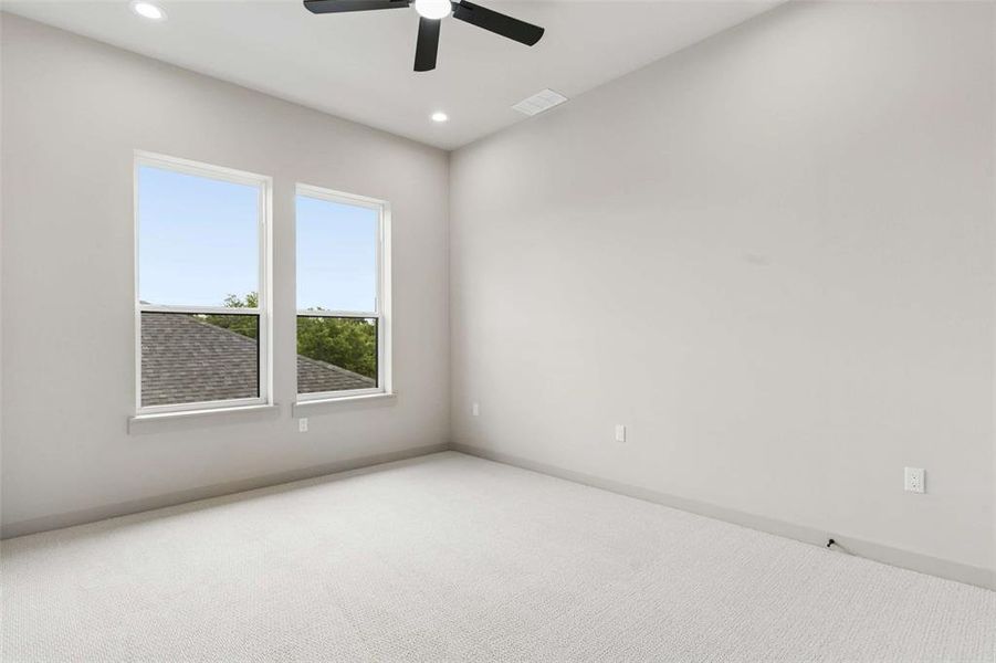 Spacious room featuring dual windows, recessed lighting, a ceiling fan, and light-toned carpeting Spacious room featuring dual windows, recessed lighting, a ceiling fan, and light-toned carpeting