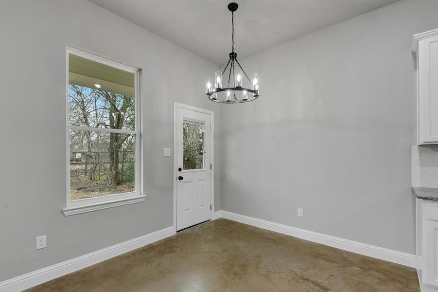 Unfurnished dining area with finished concrete flooring and a chandelier