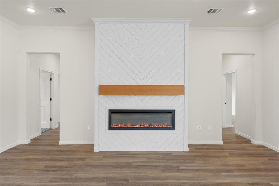 Unfurnished living room featuring recessed lighting, crown molding, a large fireplace, and wood finished floors Unfurnished living room featuring recessed lighting, crown molding, a large fireplace, and wood finished floors