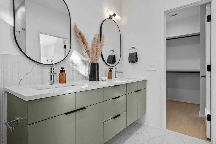 Primary Bathroom featuring elegant light marble finish floors, double vanity, and a walk in closet Primary Bathroom featuring elegant light marble finish floors, double vanity, and a walk in closet