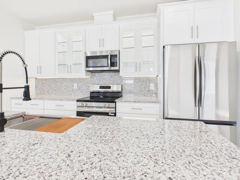 Kitchen with stainless steel appliances, light stone countertops, backsplash, and glass insert cabinets Kitchen with stainless steel appliances, light stone countertops, backsplash, and glass insert cabinets