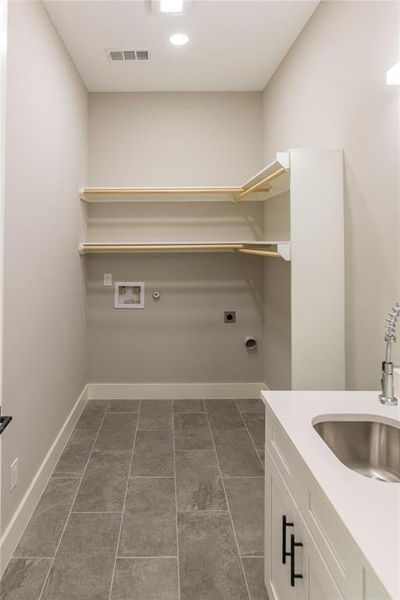 Laundry room with sink, hookup for a washing machine, electric dryer hookup, and dark tile flooring