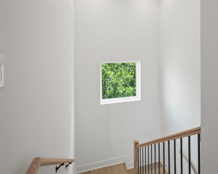 A thoughtfully placed picture window fills the stairwell with natural light and serene treetop views.