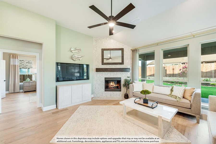Living room with tile fireplace, ceiling fan, hardwood floors, and large windows overlooking backyard