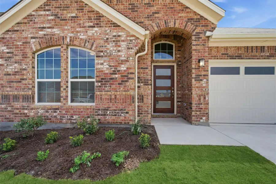 Doorway to property featuring brick siding, an attached garage, and driveway