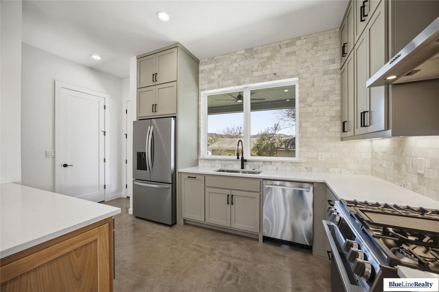 Kitchen with stainless steel appliances, gray cabinets, finished concrete floors, extractor fan, and recessed lighting