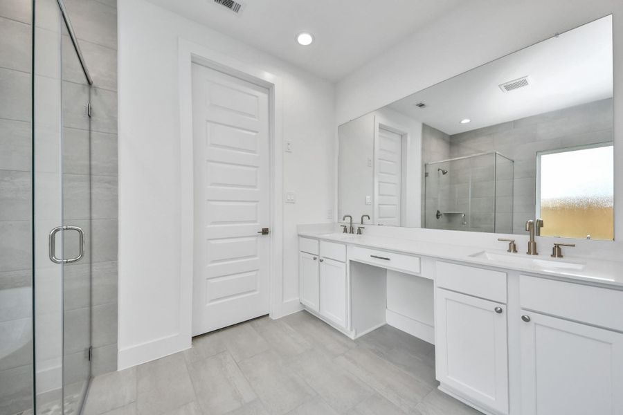 Elevate your daily routine at the elegant vanity, now equipped with double sinks, light countertops, modern hardware, and beautiful recessed lights.