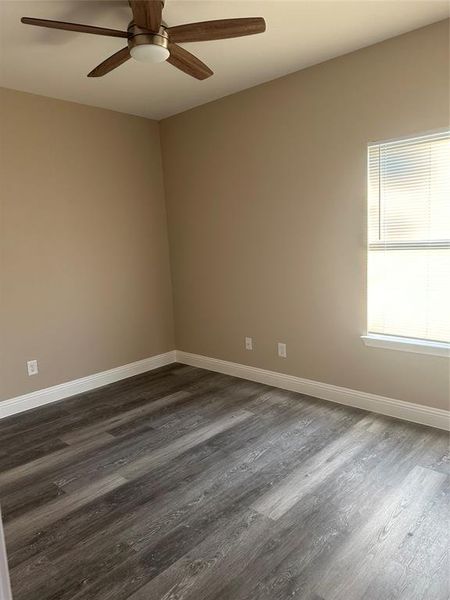 Spare room with dark wood-type flooring, baseboards, and ceiling fan