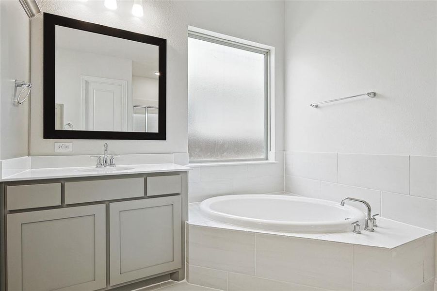 Bathroom featuring tiled bath and vanity