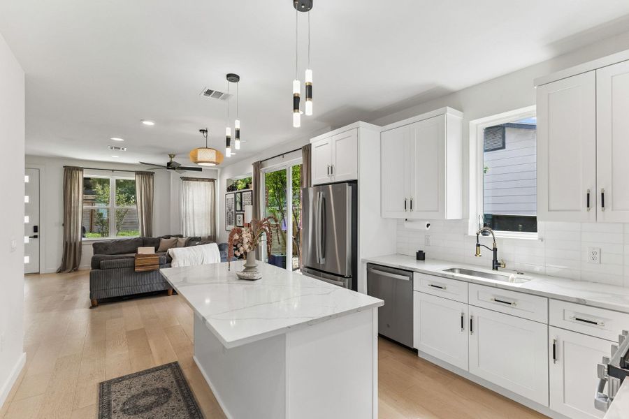A perspective from behind the kitchen island looking back toward the living room and sliding glass patio doors. This angle emphasizes the home’s layout, perfect for entertaining, with plenty of natural light flooding the entire first floor.