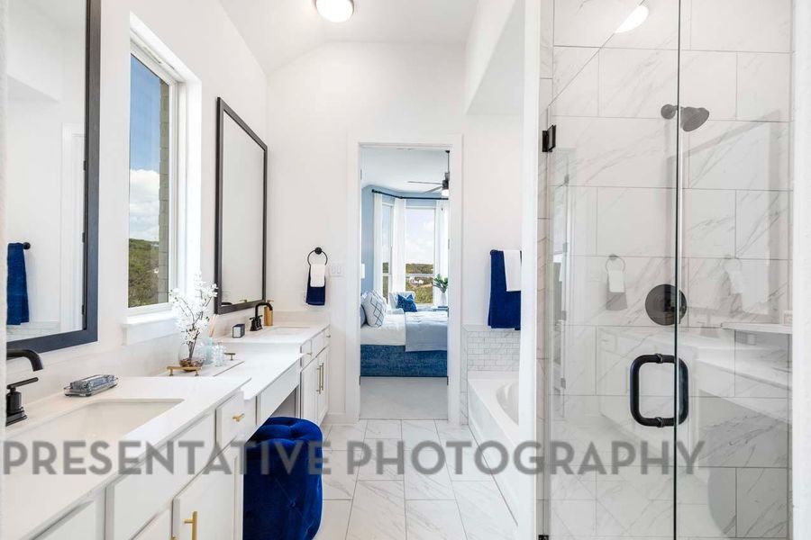 Bathroom featuring double vanity, a stall shower, a sink, vaulted ceiling, and ensuite bath