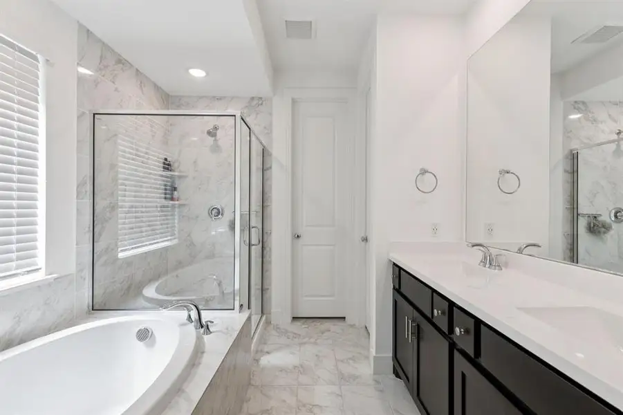Bathroom featuring a bath, a marble finish shower, light marble finish flooring, double vanity, and recessed lighting Bathroom featuring a bath, a marble finish shower, light marble finish flooring, double vanity, and recessed lighting