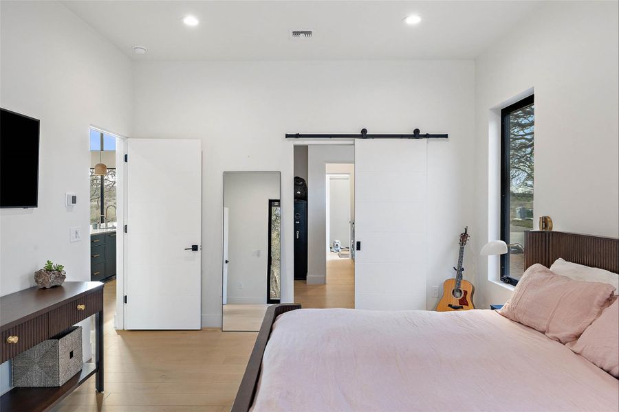 Bedroom with a barn door, light wood-type flooring, and recessed lighting