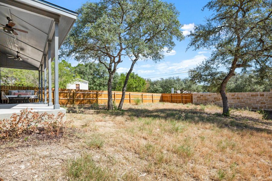Fenced backyard featuring ceiling fan