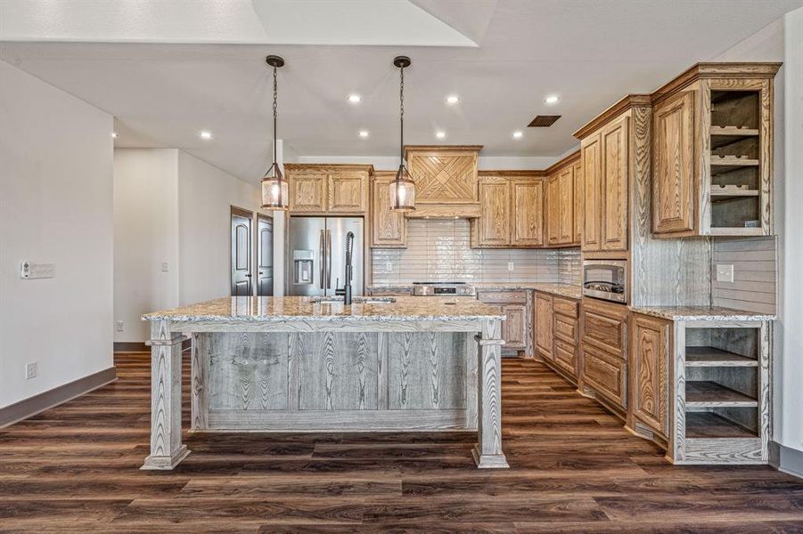 Kitchen featuring open shelves, tasteful backsplash, recessed lighting, pendant lighting, and a kitchen island with sink