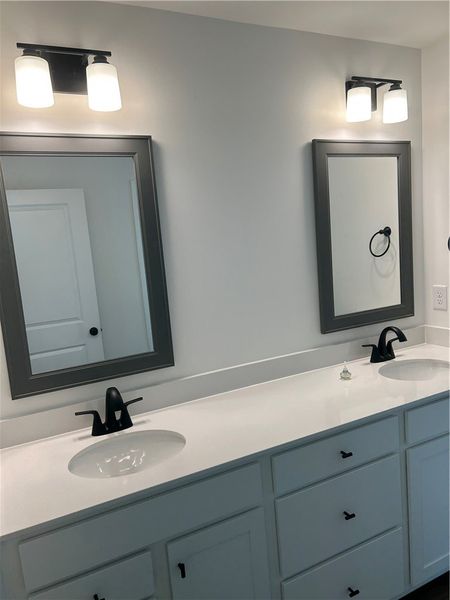 A well-lit primary bathroom features double vanity A well-lit primary bathroom features double vanity
