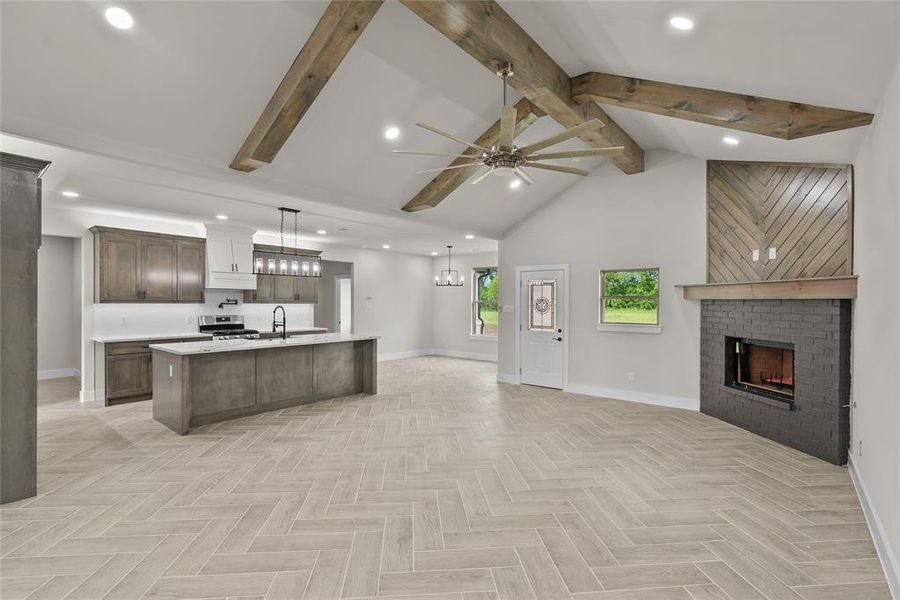 Kitchen featuring open floor plan, baseboards, ceiling fan, light countertops, and beamed ceiling