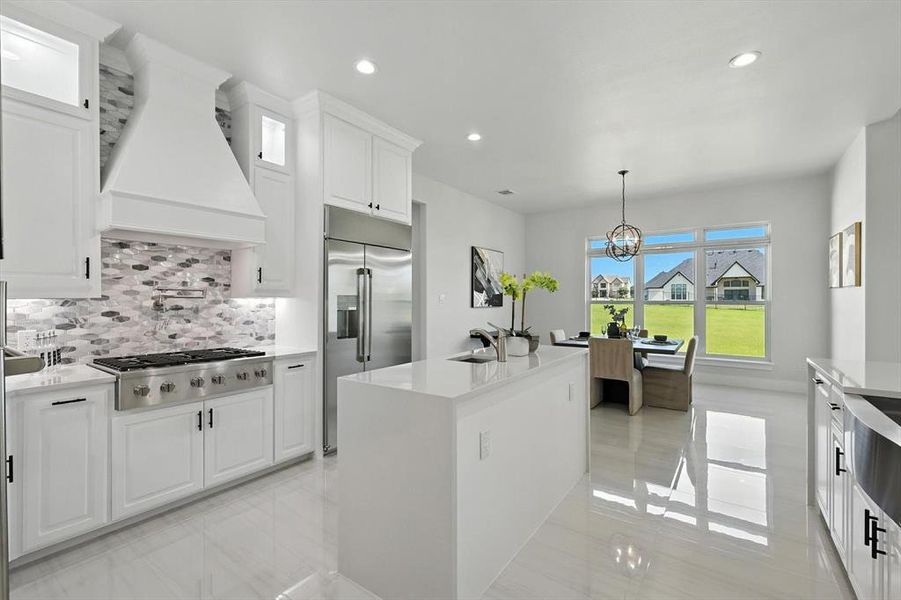 Kitchen with appliances with stainless steel finishes, white cabinets, premium range hood, decorative backsplash, and light countertops Kitchen with appliances with stainless steel finishes, white cabinets, premium range hood, decorative backsplash, and light countertops