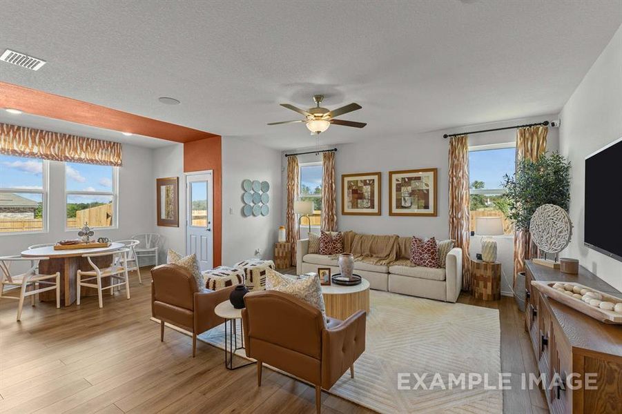 Living room with ceiling fan, a textured ceiling, and light wood-type flooring