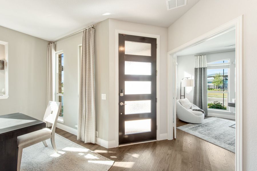 Entryway with dark front door featuring glass panels, hardwood floors, and view into adjacent living room
