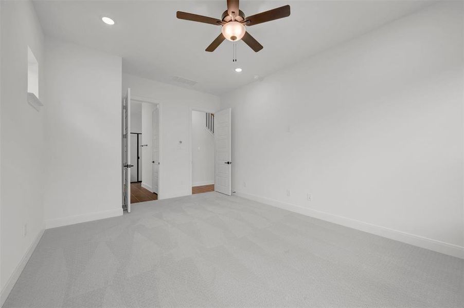 The property features an interior room with light grey carpeting, white walls, and a ceiling fan with integrated lighting