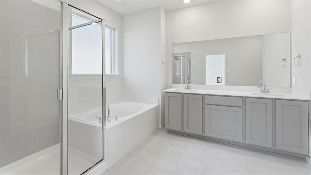 Full bath with a bath, double vanity, a shower stall, and light tile patterned floors