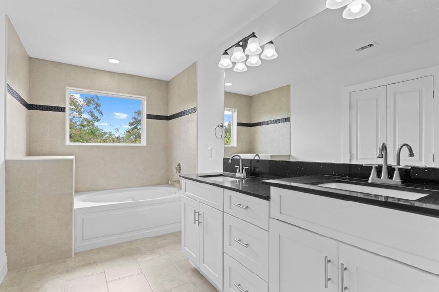 The primary spa retreat features custom cabinetry with both cabinets and drawers, giving you exceptional storage that you rarely see in most primary suites but is beautifully provided in this custom home by Next Vista Homes. Notice the deep soaker tub surrounded from ceiling to floor with stunning tile and a touch of custom accent detailing for a truly timeless look! The primary spa retreat features custom cabinetry with both cabinets and drawers, giving you exceptional storage that you rarely see in most primary suites but is beautifully provided in this custom home by Next Vista Homes. Notice the deep soaker tub surrounded from ceiling to floor with stunning tile and a touch of custom accent detailing for a truly timeless look!
