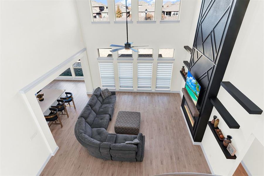 Living room with a fireplace, light wood finished floors, and a towering ceiling Living room with a fireplace, light wood finished floors, and a towering ceiling