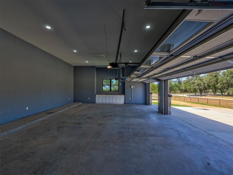 Recessed lighting illuminates this clean garage space featuring durable concrete floors and convenient built-in cabinetry.
