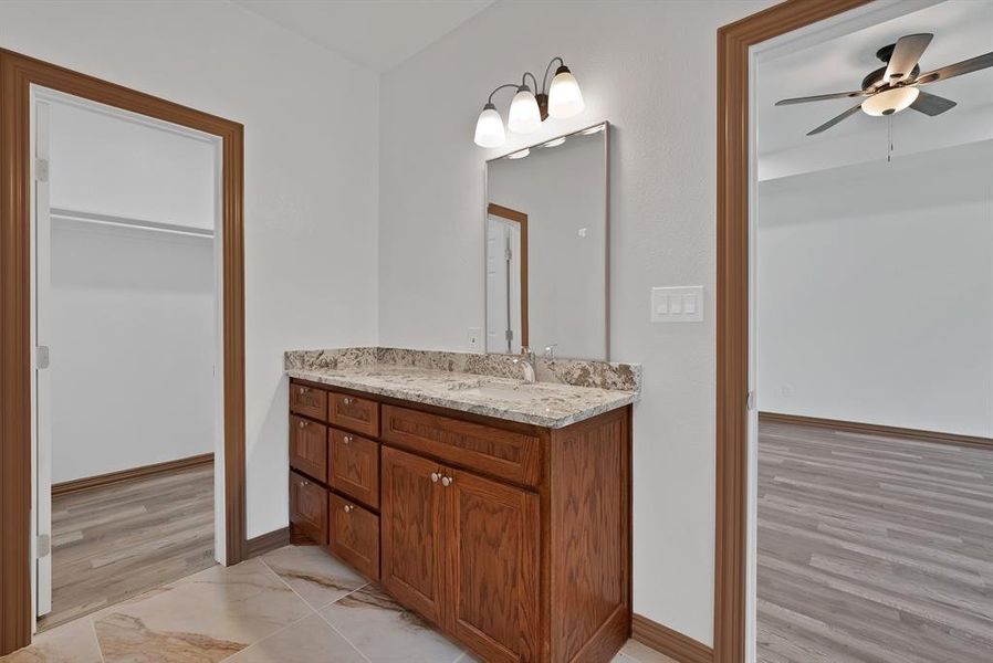 Bathroom featuring vanity, ceiling fan, light wood-style flooring, and a walk in closet