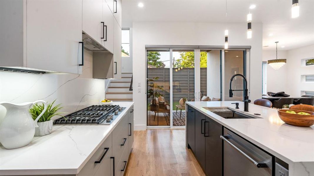 Kitchen with a center island with sink, light wood-type flooring, pendant lighting, sink, and appliances with stainless steel finishes