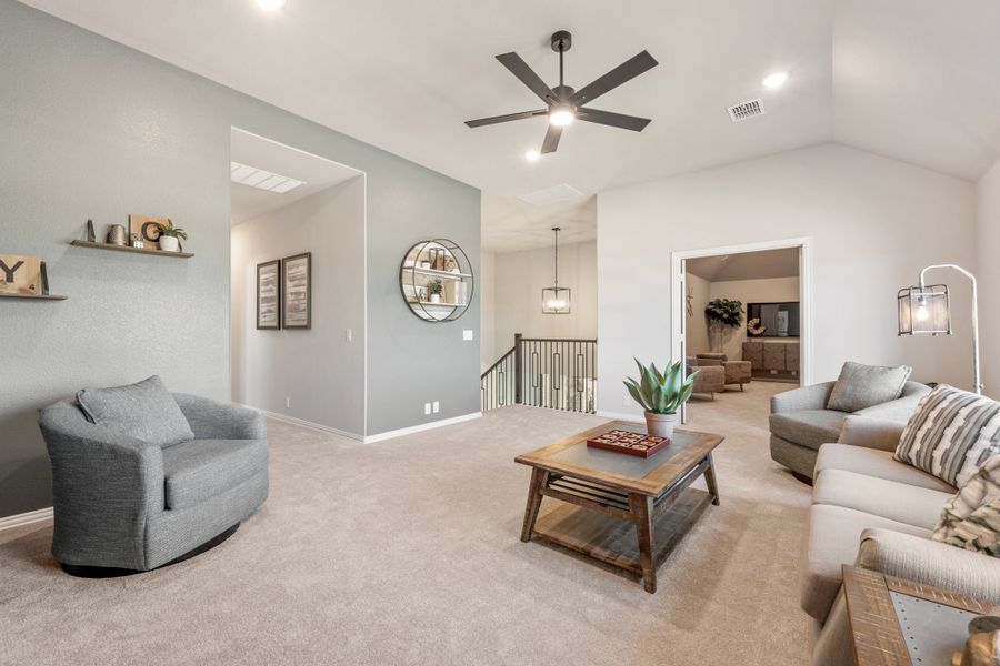 Upstairs living area with vaulted ceiling, ceiling fan, carpet flooring, and open railing staircase nearby