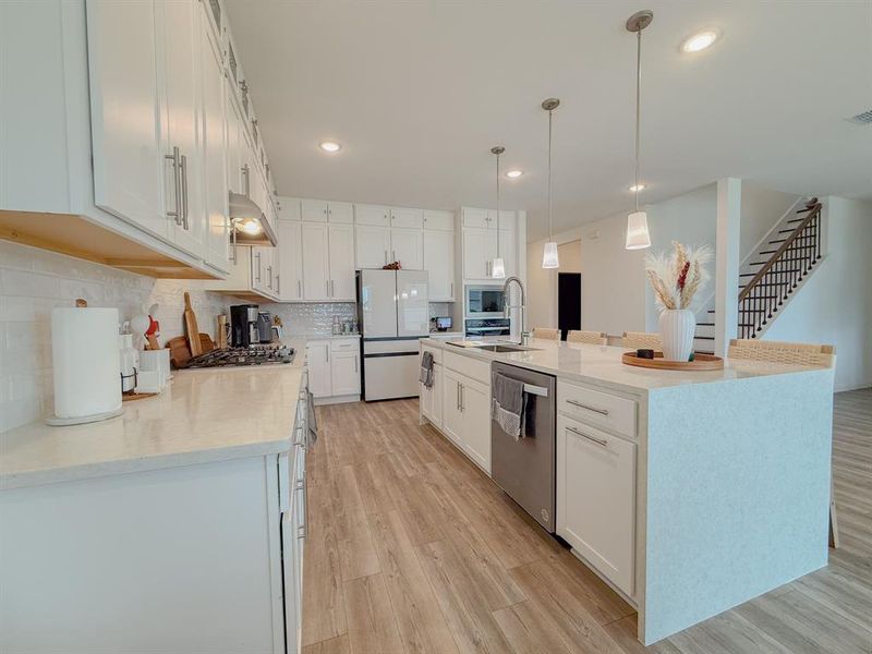 Kitchen featuring light wood-style floors, white cabinetry, appliances with stainless steel finishes, and backsplash