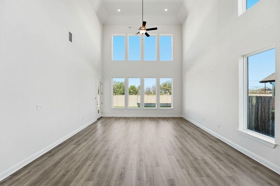 Unfurnished living room featuring light wood finished floors, a high ceiling, ceiling fan, and recessed lighting