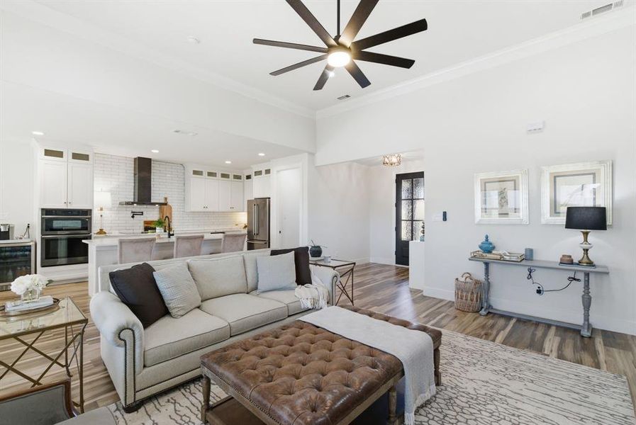 Living area featuring light wood finished floors, ornamental molding, wine cooler, ceiling fan, and recessed lighting