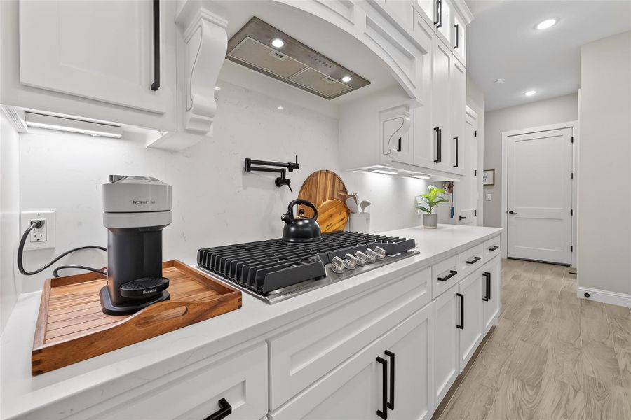 Cooking area with decorative vent hood and custom cabinetry. Cooking area with decorative vent hood and custom cabinetry.